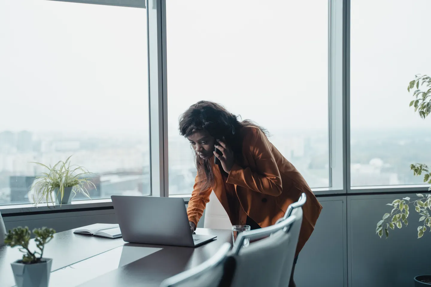 A person working at a laptop beside large office windows